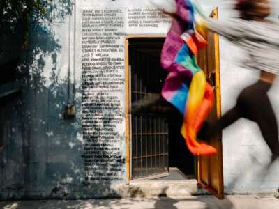 Kha'Dija Mendheim runs by holding a Pride flag in front of a Pulse nightclub memorial mural at Pridelines in Miami, Florida, on May 3, 2023.