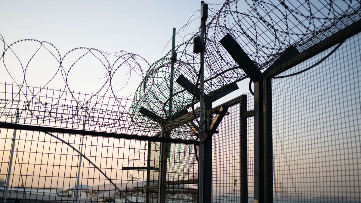 Iron mesh prison fence topped with barbed wire