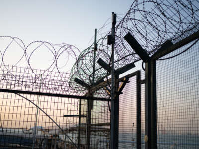 Iron mesh prison fence topped with barbed wire