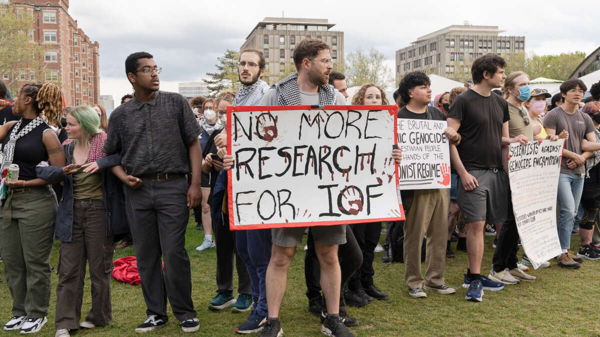 A pro-Palestine protester holds a placard that says, "No more research for IOF (Israeli Occupation Forces)" during a 2024 rally at the Massachusetts Institute of Technology (MIT) campus as student demonstrators demand divestment from Israeli military ties.