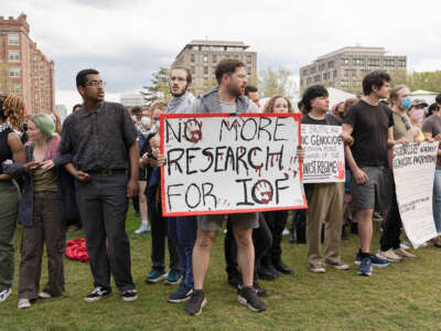 A pro-Palestine protester holds a placard that says, "No more research for IOF (Israeli Occupation Forces)" during a 2024 rally at the Massachusetts Institute of Technology (MIT) campus as student demonstrators demand divestment from Israeli military ties.