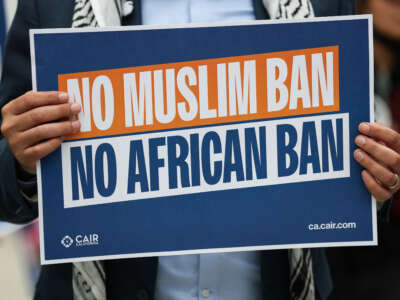 A man holds a placard as demonstrators gather to protest against a sweeping travel ban announced by U.S. President Donald Trump, outside the Tom Bradley International Terminal at Los Angeles International Airport in California, on June 9, 2025.