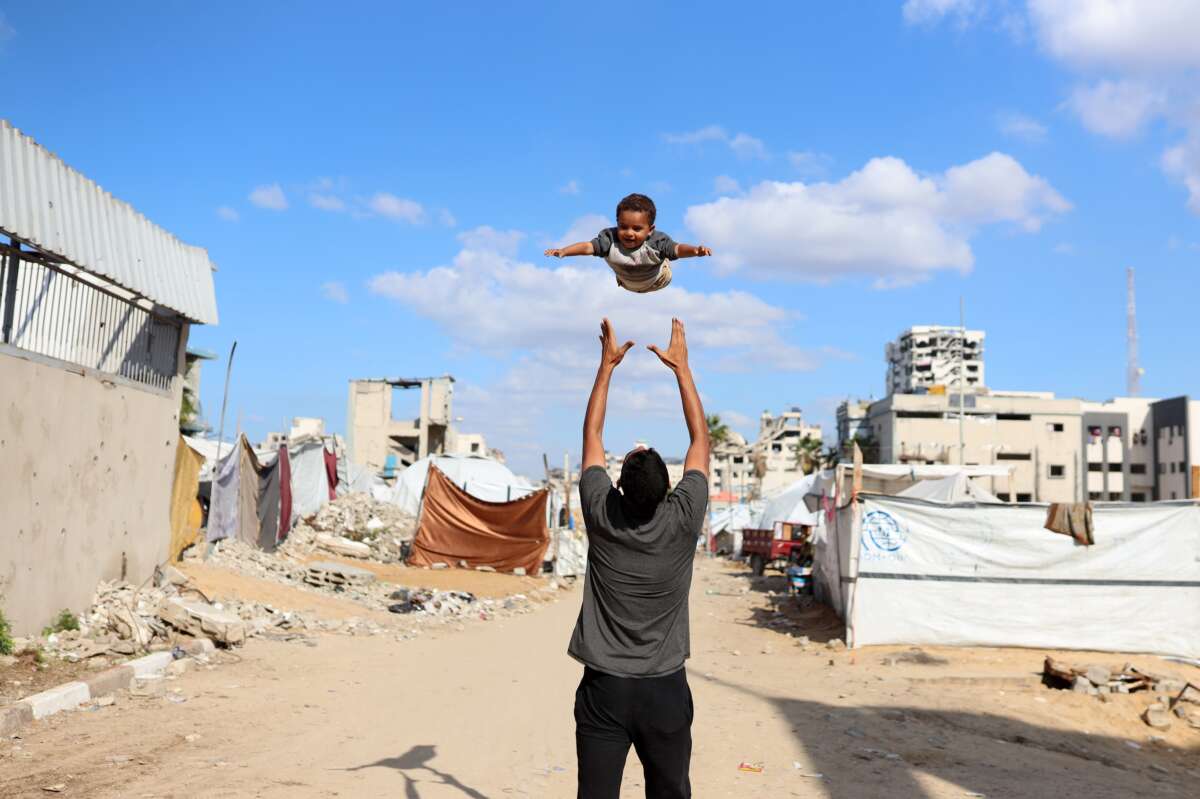 A displaced Palestinian man plays with his son in a displacement camp in Gaza City, Palestine, on November 26, 2025.