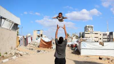 A displaced Palestinian man plays with his son in a displacement camp in Gaza City, Palestine, on November 26, 2025.