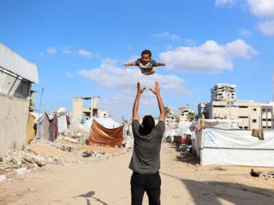A displaced Palestinian man plays with his son in a displacement camp in Gaza City, Palestine, on November 26, 2025.