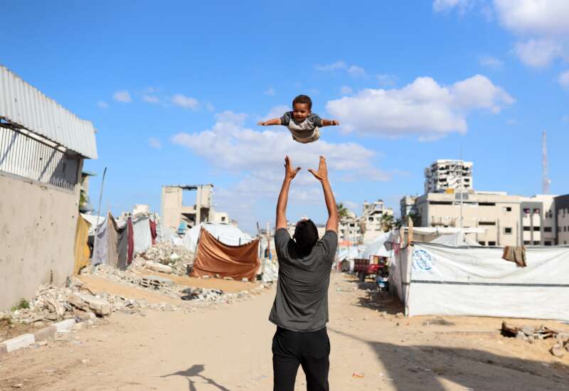 A displaced Palestinian man plays with his son in a displacement camp in Gaza City, Palestine, on November 26, 2025.