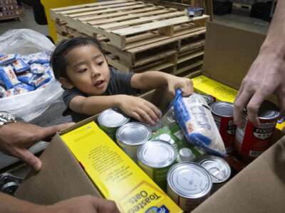 A child helps load food boxes during at the OC Food Bank in Garden Grove, California, on January 19, 2026. Recent survey data finds that 55 percent of low-income families with children have had to cut back on groceries recently to make ends meet.