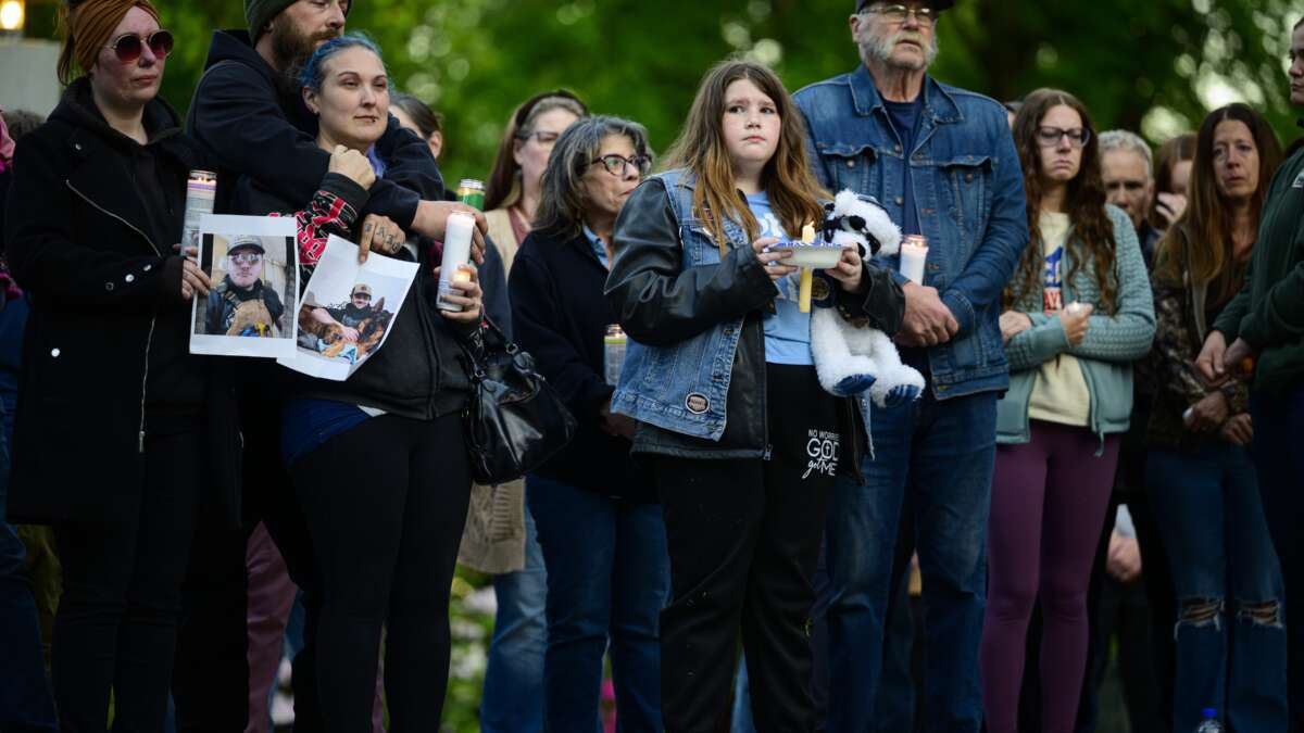 Community members hold photographs of loved ones during a vigil at R.A. Long Park following a fatal chemical storage tank failure on May 26, 2026, in Longview, Washington.