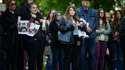 Community members hold photographs of loved ones during a vigil at R.A. Long Park following a fatal chemical storage tank failure on May 26, 2026, in Longview, Washington.