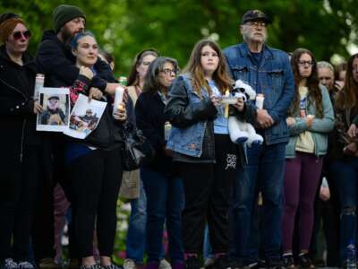 Community members hold photographs of loved ones during a vigil at R.A. Long Park following a fatal chemical storage tank failure on May 26, 2026, in Longview, Washington.
