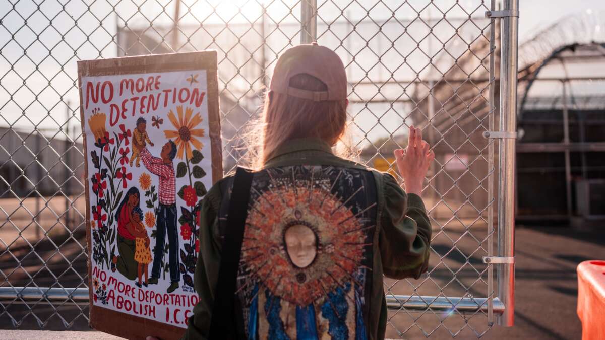 A protester holds a sign by the outer fence at Delaney Hall Immigration Detention Center on June 4, 2026, in Newark, New Jersey.