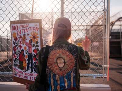 A protester holds a sign by the outer fence at Delaney Hall Immigration Detention Center on June 4, 2026, in Newark, New Jersey.