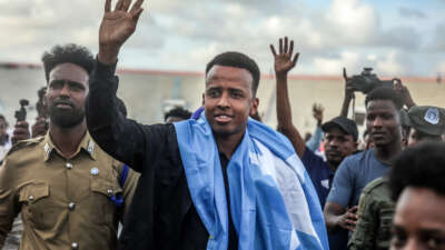 Somali referee Omar Artan waves to supporters while draped in the Somali flag upon returning to Mogadishu, on June 10, 2026.