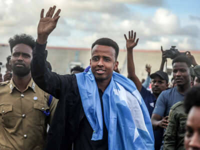 Somali referee Omar Artan waves to supporters while draped in the Somali flag upon returning to Mogadishu, on June 10, 2026.