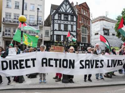Protesters hold a banner outside the Royal Courts of Justice in central London on June 15, 2026, as the High Court rules on a legal standoff between the government and activist group Palestine Action.