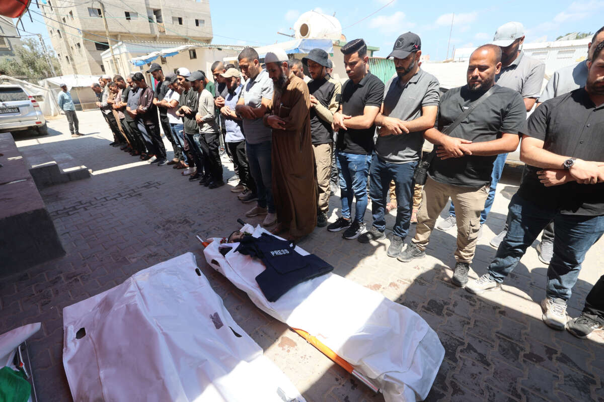 Friends and relatives of Al Jazeera video journalist Ahmed Wishah, who was killed in an Israeli strike the previous day, pray over his body at Al-Aqsa Martyrs Hospital in Deir el-Balah in the central Gaza Strip on June 21, 2026. The Israeli military said that Ahmed Wishah was killed alongside two other Hamas militants and that he had served as a "operative in Hamas's military wing," but did not provide any evidence to support the accusation.