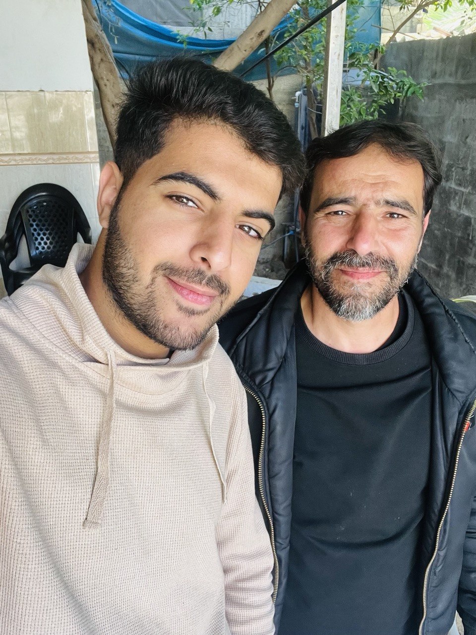 Hassan Herzallah stands with his father in a restaurant in Gaza on October 6, 2023, one day before the genocide began.