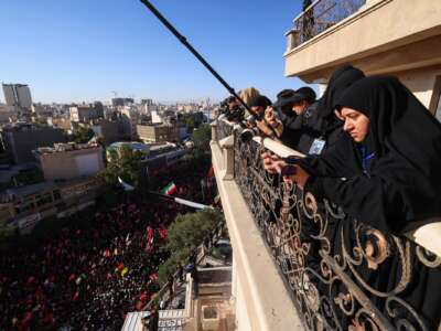 Photographers take pictures of crowds of mourners as they surround the convoy carrying the coffins of Iran's slain supreme leader Ali Khamenei and members of his family during a funeral procession, before he is buried at the Shrine of Imam Reza, Iran's most revered place of worship, in Mashhad on July 9, 2026.