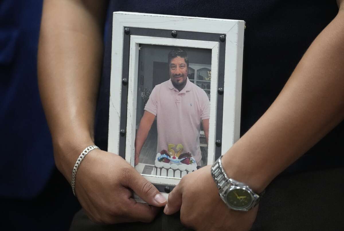 Ronaldo Salgado, son of Lorenzo Salgado Araujo, holds a photo of his father during a news conference about the ICE shooting death in Houston Wednesday, July 8, 2026.