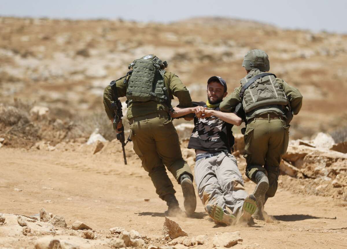 Israeli forces remove a demonstrator during a demonstration by Palestinians and international activists on July 1, 2022, in the Al-Jawaya in Masafer Yatta area in the Israeli-occupied West Bank.