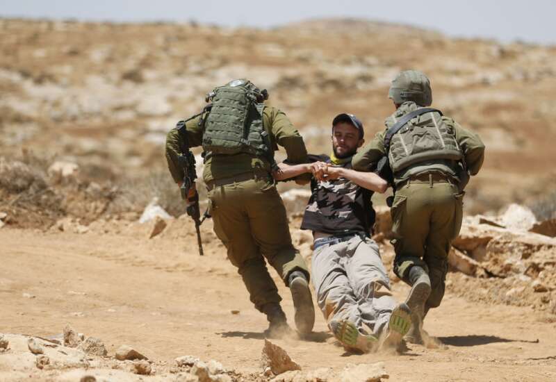 Israeli forces remove a demonstrator during a demonstration by Palestinians and international activists on July 1, 2022, in the Al-Jawaya in Masafer Yatta area in the Israeli-occupied West Bank.