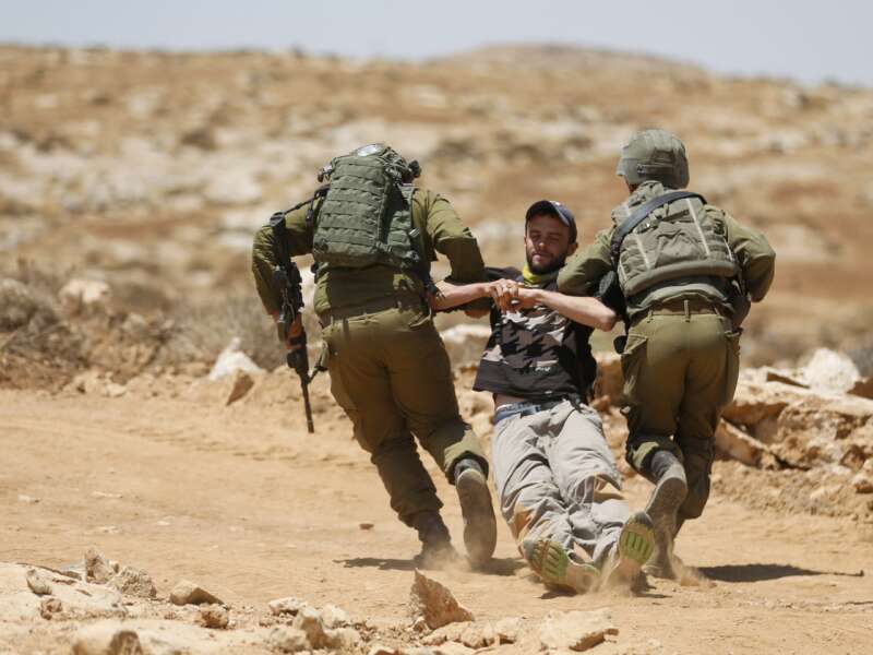 Israeli forces remove a demonstrator during a demonstration by Palestinians and international activists on July 1, 2022, in the Al-Jawaya in Masafer Yatta area in the Israeli-occupied West Bank.