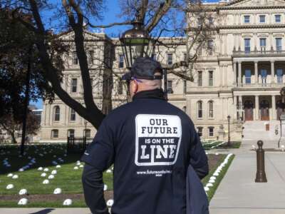 Members of the United Steelworkers union place hard hats on the lawn of the state capitol to represent the jobs they say would be lost by the closure of Enbridge Line 5, an oil pipeline that runs under the Straits of Mackinac, in Lansing, Michigan, on May 11, 2021.
