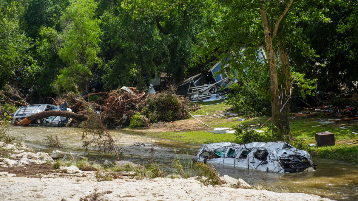 Destroyed vehicles sit in floodwaters as volunteers clean up and recover belongings on July 7, 2025, following a weekend flash flood that devastated homes in Leander, Texas. A new report from House Democrats claims the Trump administration left the U.S. unprepared for disasters by directing relief workers to support immigration enforcement.