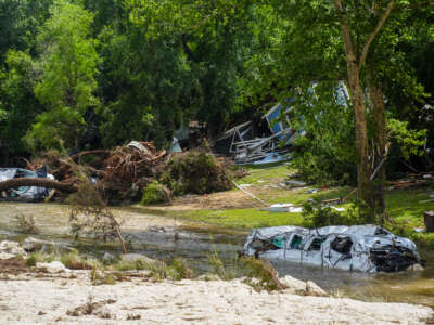 Destroyed vehicles sit in floodwaters as volunteers clean up and recover belongings on July 7, 2025, following a weekend flash flood that devastated homes in Leander, Texas. A new report from House Democrats claims the Trump administration left the U.S. unprepared for disasters by directing relief workers to support immigration enforcement.