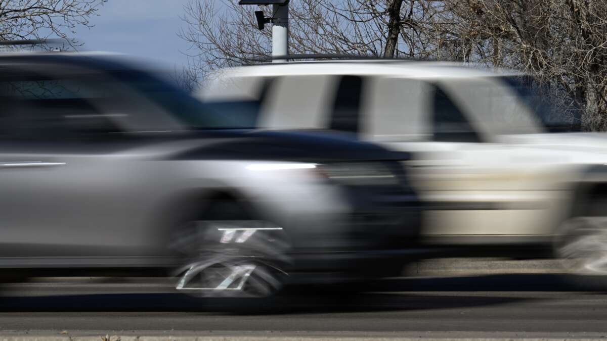 A Flock Safety license plate recognition camera is seen on a street light post as vehicles pass by in Longmont, Colorado, on December 10, 2025.