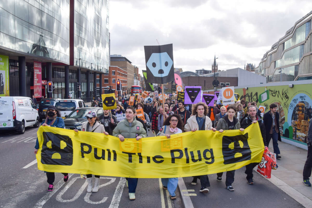 Protesters march with a 'Pull the plug' banner in King's Cross towards Meta's London offices during a demonstration against unregulated Artificial Intelligence and data centers.