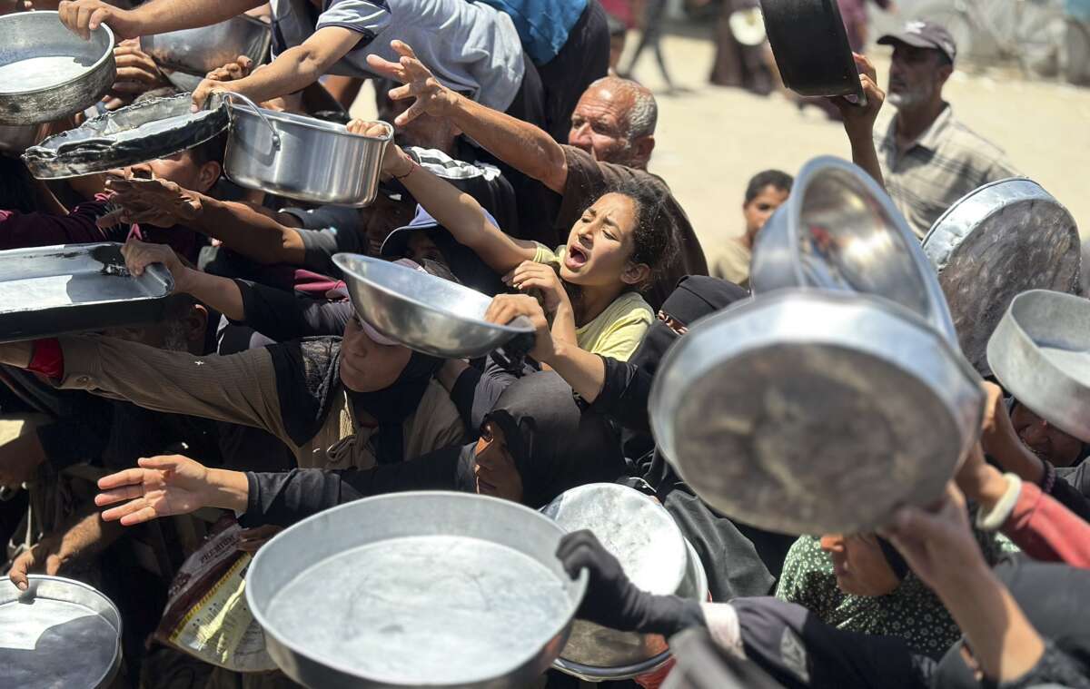 Displaced Palestinians crowd around a food distribution point at Al-Saada charity kitchen in Al-Mawasi, Khan Younis, in the Gaza Strip, on May 13, 2026. Residents fear worsening living conditions and a renewed risk of famine as food aid declines across the Gaza Strip.