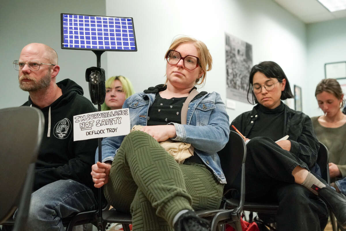 Resident Bri Harrington, center, holds a prop that reflects her feelings about the Flock cameras during a council meeting where citizens had the opportunity to speak out against the cameras during a public comment period on April 23, 2026, at city hall in Troy, New York.