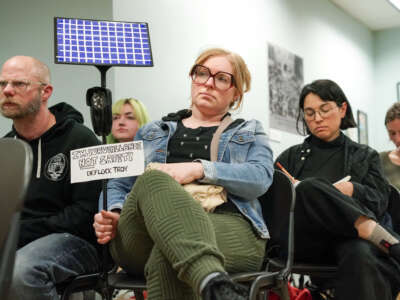 Resident Bri Harrington, center, holds a prop that reflects her feelings about the Flock cameras during a council meeting where citizens had the opportunity to speak out against the cameras during a public comment period on April 23, 2026, at city hall in Troy, New York.
