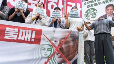 Protesters hold placards reading “Boycott Starbucks” and “resignation of Chung Yong-jin” in front of the Starbucks Korea headquarters in Seoul, South Korea, on May 23, 2026.