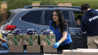 A volunteer prepares to load boxes of food into a car during a drive-thru food distribution at Montebello Golf Course on May 29, 2026, in Montebello, California.