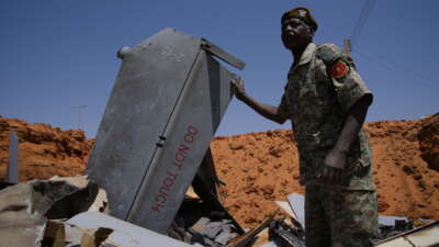 A man stands in a crater filled with drone components on March 29, 2026, in el-Obeid, Sudan.