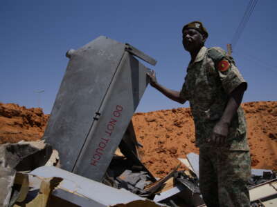 A man stands in a crater filled with drone components on March 29, 2026, in el-Obeid, Sudan.