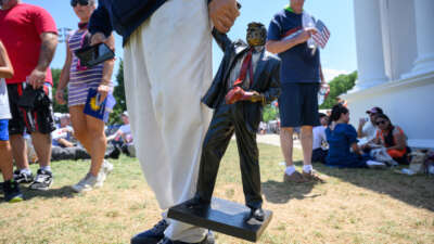A person carries a miniature statue of President Donald Trump at The Great American State Fair along the National Mall on July 4, 2026, in Washington, D.C.