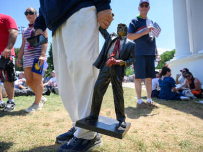 A person carries a miniature statue of President Donald Trump at The Great American State Fair along the National Mall on July 4, 2026, in Washington, D.C.