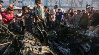 People inspect a car that was destroyed by Israeli air strikes on July 8, 2026, in Gaza City, Gaza.