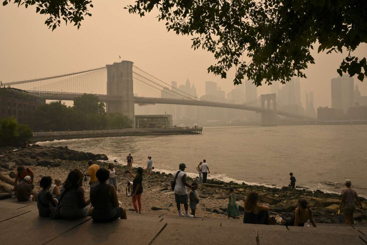 People near the Brooklyn Bridge look on as wildfire smoke from Canada causes hazy conditions in New York City, on July 16, 2026. Out-of-control wildfires in Ontario, Canada, prompted evacuations and sent dangerous smoke billowing into the U.S. where millions of people were exposed to the unhealthy air.