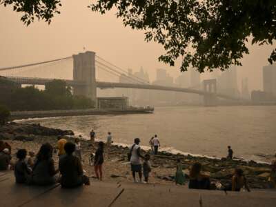 People near the Brooklyn Bridge look on as wildfire smoke from Canada causes hazy conditions in New York City, on July 16, 2026. Out-of-control wildfires in Ontario, Canada, prompted evacuations and sent dangerous smoke billowing into the U.S. where millions of people were exposed to the unhealthy air.