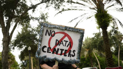 A person holds signs during a nationwide protest against AI data center expansion outside Peace Hall in New Port Richey, Florida, on July 18, 2026.