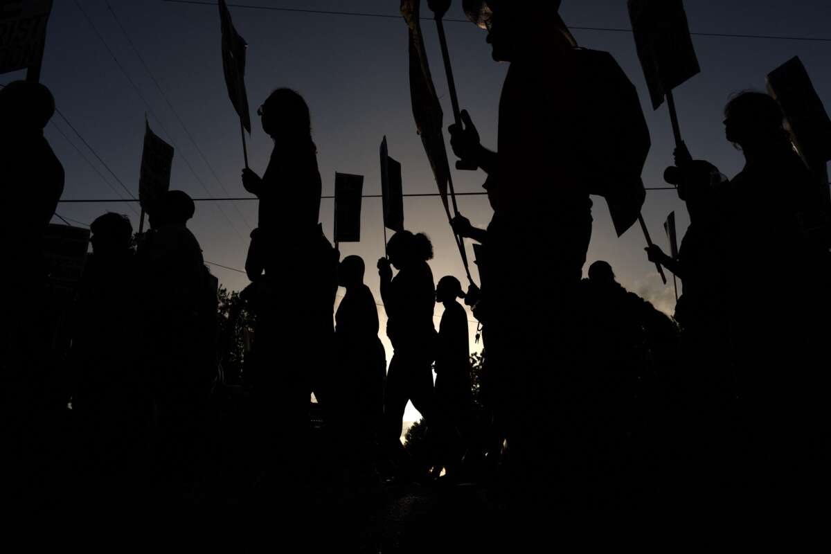 People hold signs while marching through the Magnolia Park neighborhood of Houston, Texas, during a rally to protest the killing of Lorenzo Salgado Araujo, on July 24, 2026.