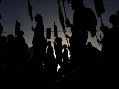 People hold signs while marching through the Magnolia Park neighborhood of Houston, Texas, during a rally to protest the killing of Lorenzo Salgado Araujo, on July 24, 2026.