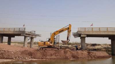 An excavator works on the Gachin Bridge, which was damaged by a UsSs strike, along the road between Bandar Abbas and Bandar Khamir, southern Iran on August 11, 2026.
