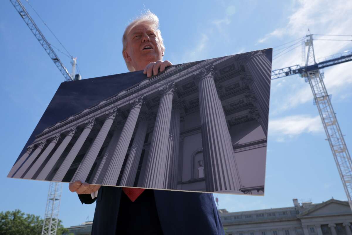 President Donald Trump holds artists renderings as he talks to reporters about his proposed White House ballroom next to the worksite on May 19, 2026 in Washington, D.C.