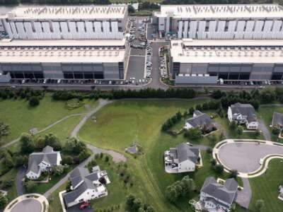 This aerial view shows an Amazon Web Services (AWS) data center adjacent to single-family homes in Stone Ridge, Virginia on August 12, 2026. Hastily built to meet skyrocketing demand for computing power required by the global artificial intelligence race, data centers are facing opposition across the United States.