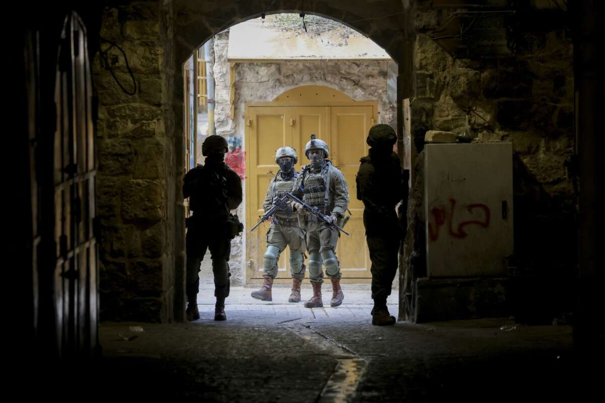 Armed Israeli soldiers patrol an alleyway in the Old City of Hebron, in the occupied West Bank, on August 15, 2026. The area is routinely secured by troops to allow Israeli settlers to tour the city.